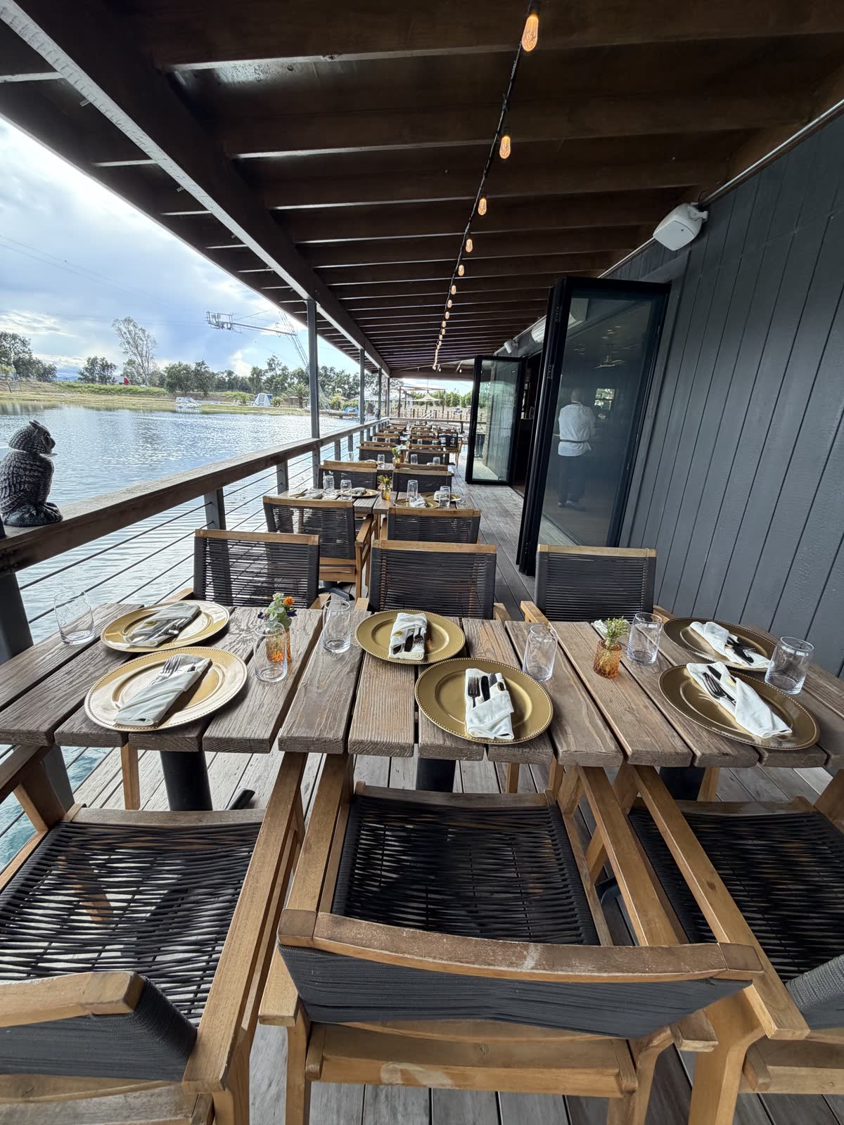 Costa Fuego deck over the water, tables set with gold chargers under string lights