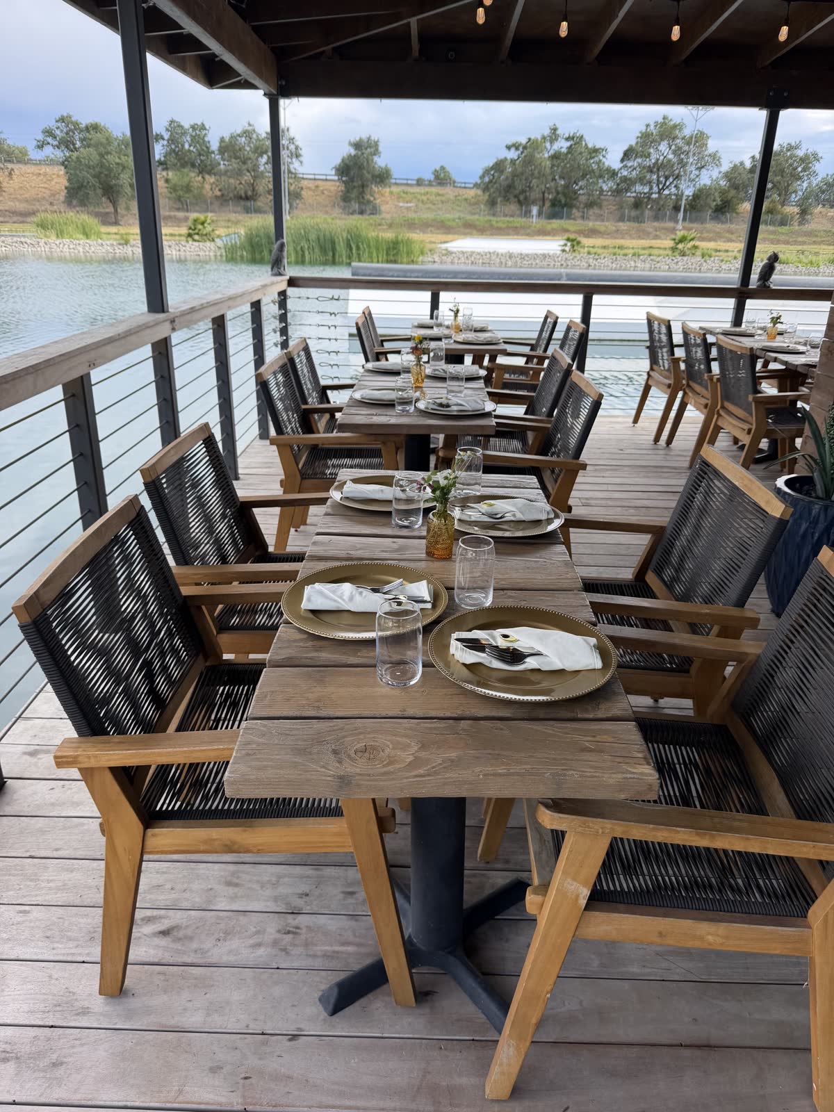 Set tables with gold chargers on the Costa Fuego deck over the lake