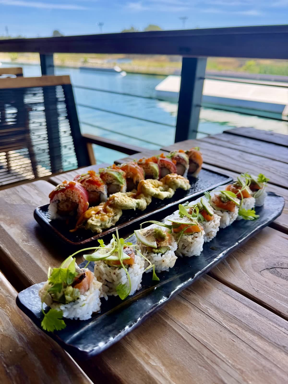 Sushi platters catered on a deck table with the lake behind